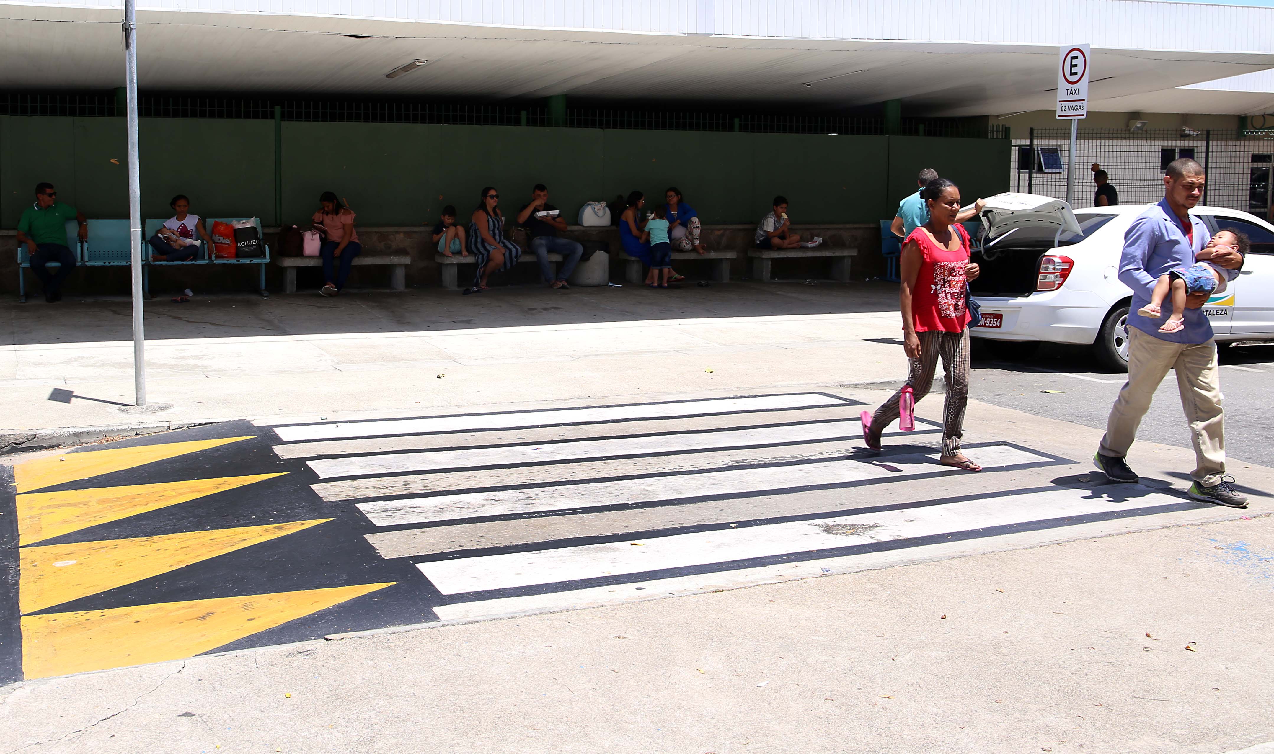 homem atravessa uma faixa elevada de pedestre com uma criança no colo